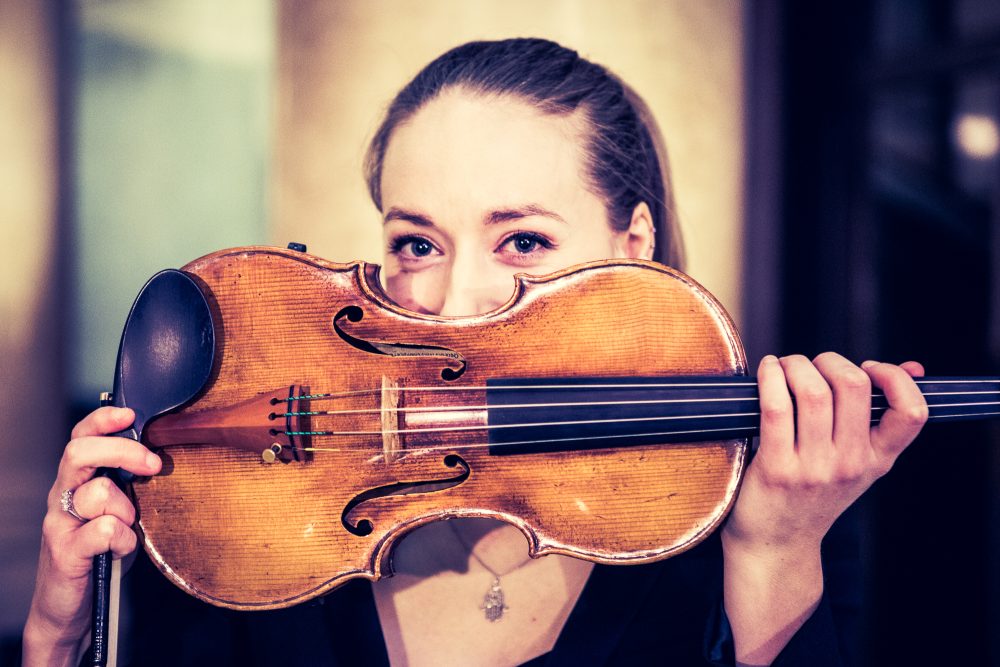 a woman holding a fiddle in front of her face