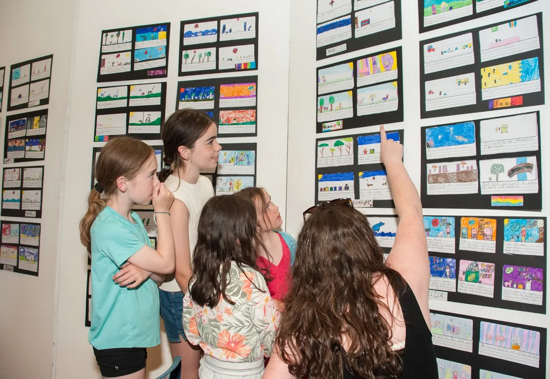 Children pointing at artwork during a school art exhibition