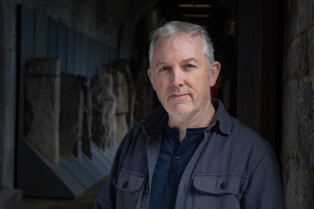 Photo of a man in grey and blue shirtd
