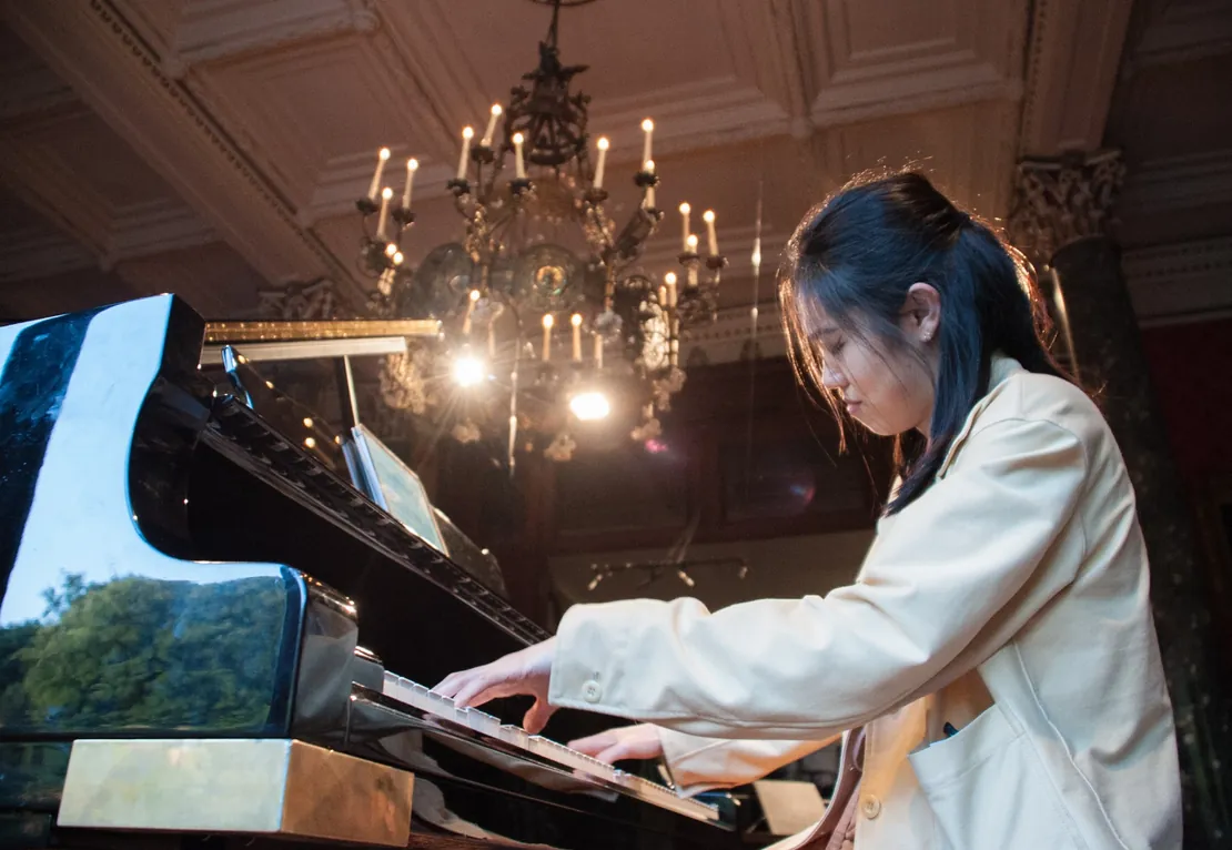 Young pianist performing on a grand piano in an ornate concert hall