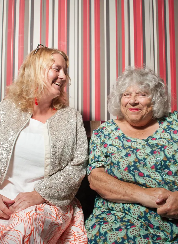 Older women smiling at camera in front of striped wall