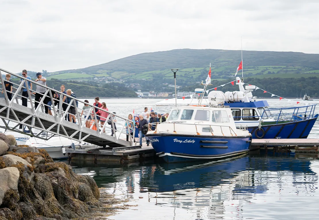 People walking up bridge off boat