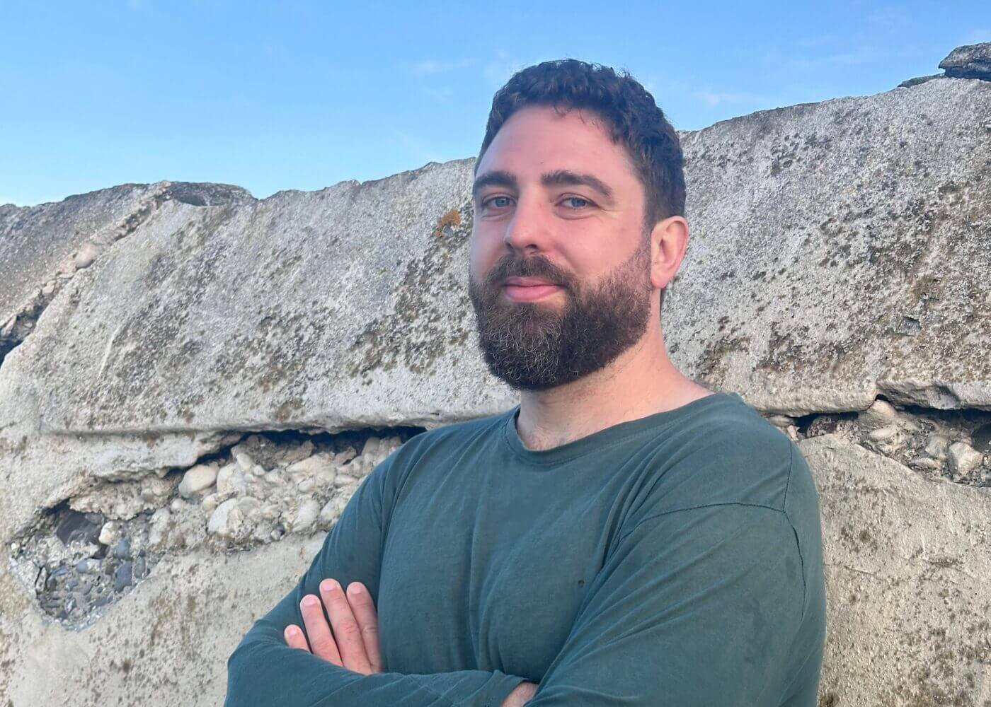 Eoghan Ó Ceannabháin stood in front of a stone face and blue sky