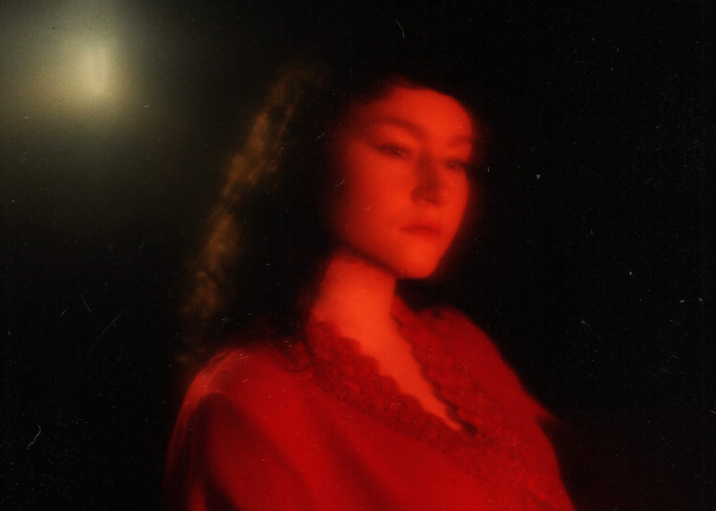 A woman wearing red in red light with a dark background