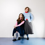 Lemoncello, Two women one sat one standing in front of white back drop