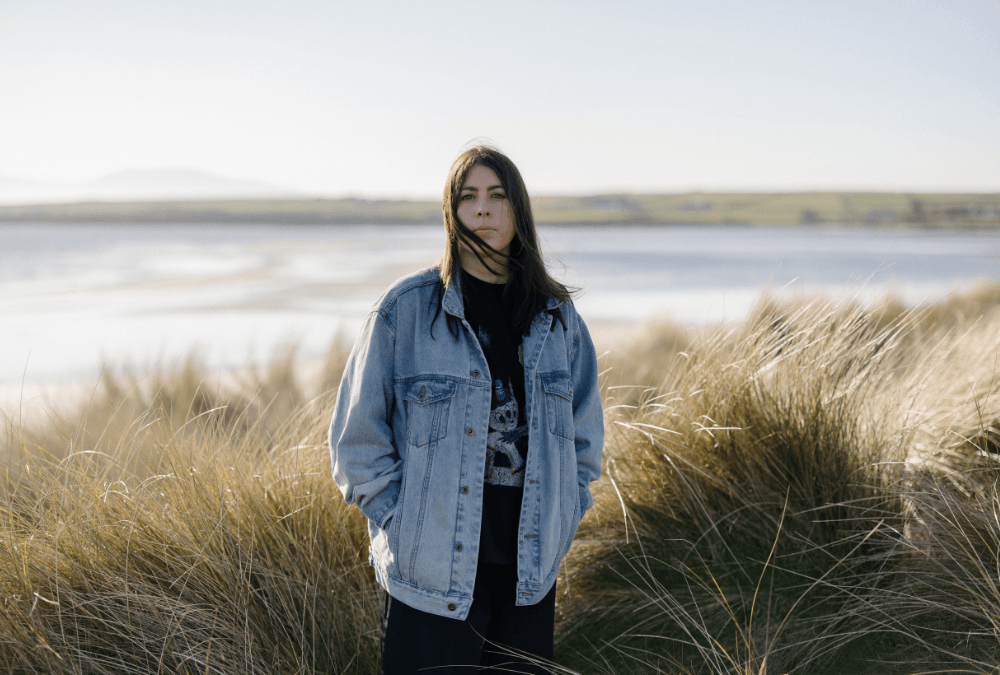 Sorcha Richardson standing in front of grassy sand dunes