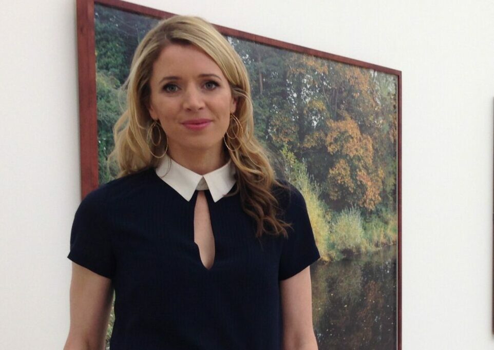 Nadine O'Regan standing in front of a painting in a gallery